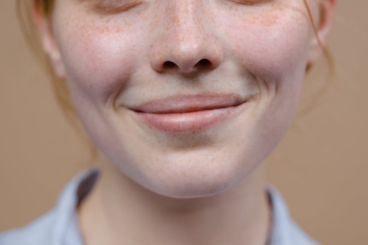 Photo by Tima Miroshnichenko A close-up image capturing the subtle smile and freckles of a woman.