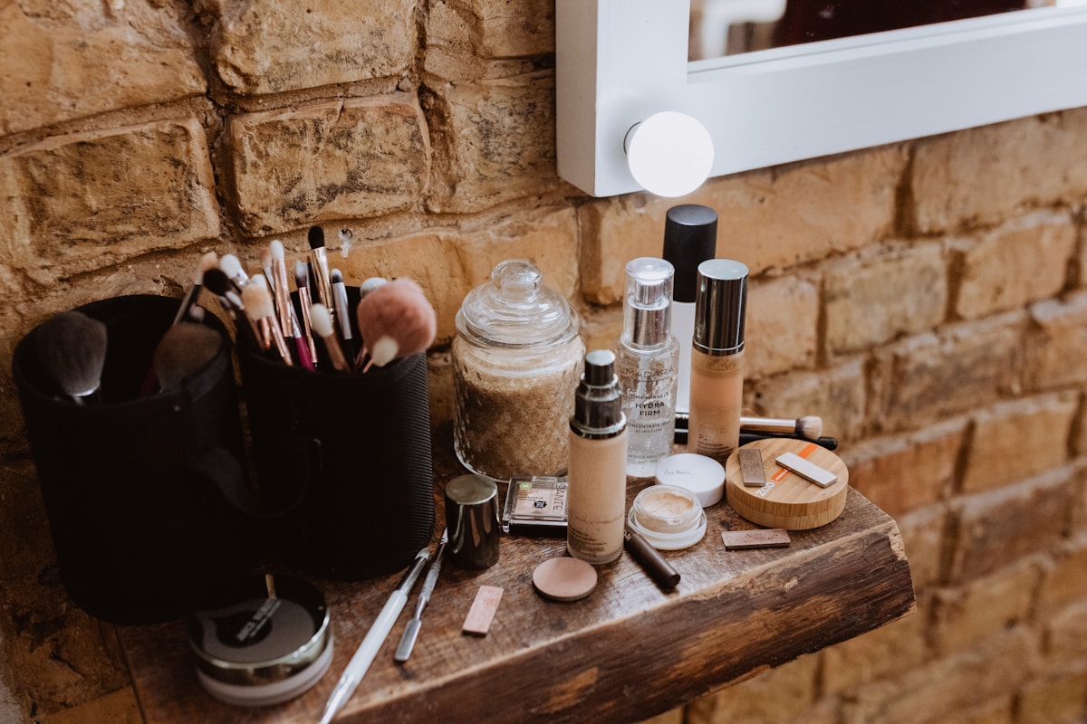a wooden table topped with makeup and brushes
